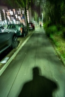 Pedestrian path in the evening, dark, little lighting from street lamps, shadow of a man, following