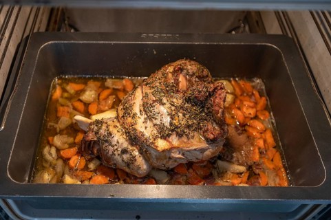 Freshly roasted roast lamb with herbs and vegetables in a casserole in the oven, Bavaria, Germany,