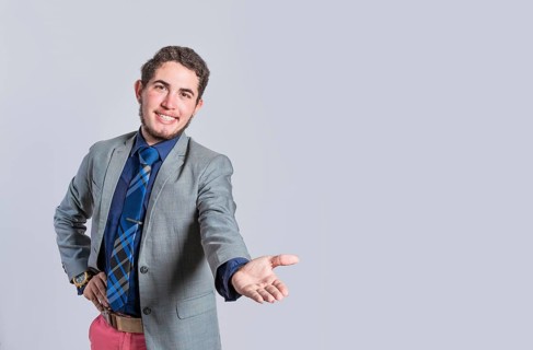 Man extending his hand inviting, man in suit welcoming, man looking at camera presenting a product,