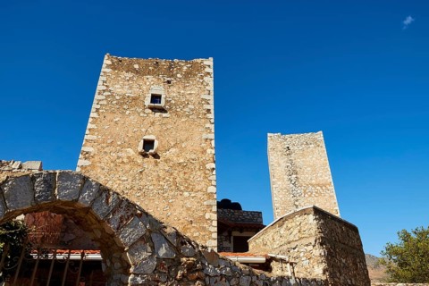 Stone towers of an ancient structure with an arch and blue sky in the background, Flomochori,