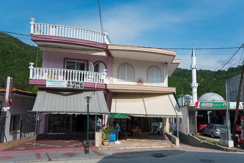 A two-storey building with a shop on the ground floor and a small minaret next to it, Typical