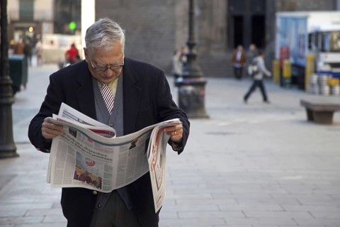 Elderly man reading newspaper in the streets of the old Barri Gòtic, Gothic quarter of Barcelona,