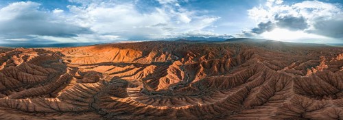 Panorama, landscape of eroded hills at Lake Issyk Kul, badlands at sunset, mountain peaks of the
