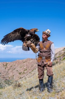 Traditional Kyrgyz eagle hunter with eagle in the mountains, near Kysyl-Suu, Kyrgyzstan, Asia