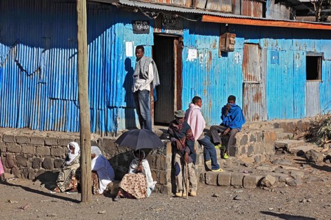 Europia district, locals waiting in front of a blue corrugated iron hut, Ethiopia, Africa