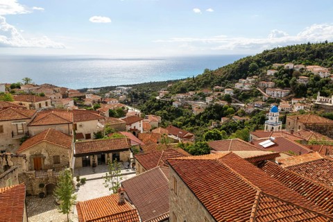 View to Ionian Sea over houses and rooftops with Greek Orthodox Church of Saint Spyridon, village