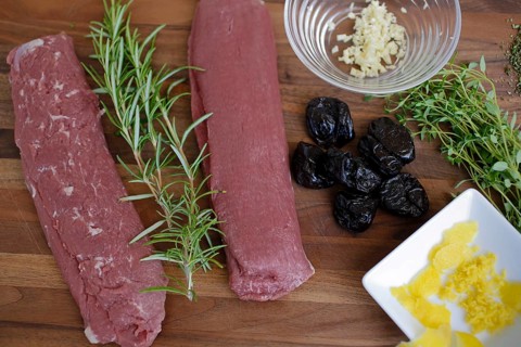 Swabian cuisine, preparation of lamb with prunes, raw lamb, rosemary, herbs, sliced garlic, lemon