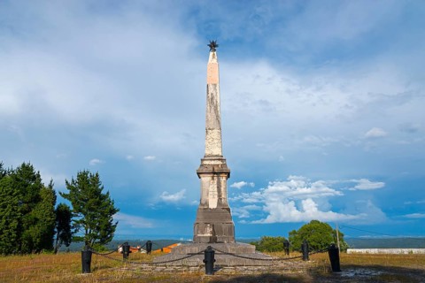 Sublime stone obelisk monument in an open field under a dramatic sky, commemorating the