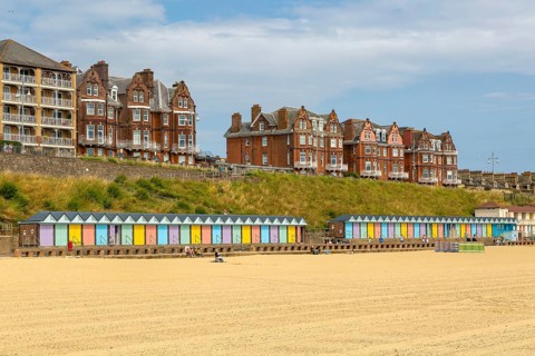 Colourful beach huts and historic clifftop buildings, South Beach, Lowestoft, Suffolk, England, UK