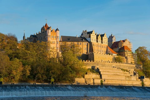 A castle on a hill above a river in autumnal surroundings with blue sky and sunset, Bernburg