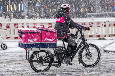 Winter weather, heavy snowfall, city centre traffic, courier of the delivery service Flink on