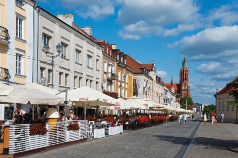 Lively street with historic houses and church tower in a summer atmosphere, Kosciuszko market