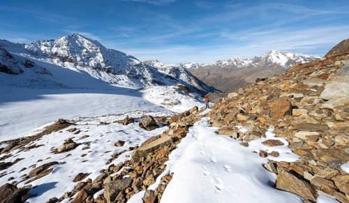 Mountaineer on a hiking trail with snow, descent from Ramoljoch at Spiegelferner, autumnal mountain