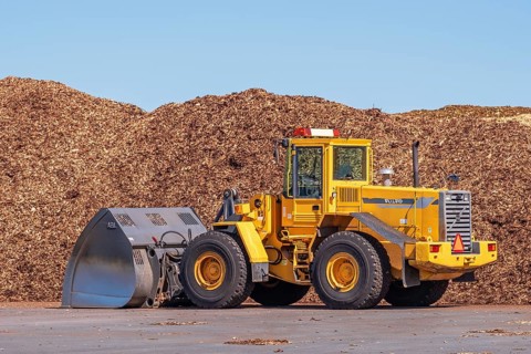 Front loader with a large bucket on a loading area for wood chips