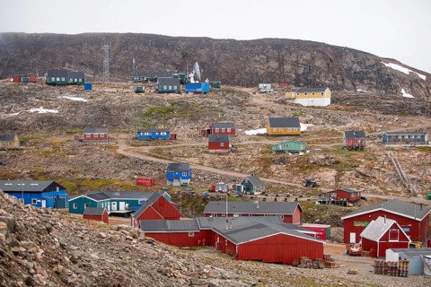 Small, colourful houses are scattered on a rocky slope, secluded Arctic Inuit settlement