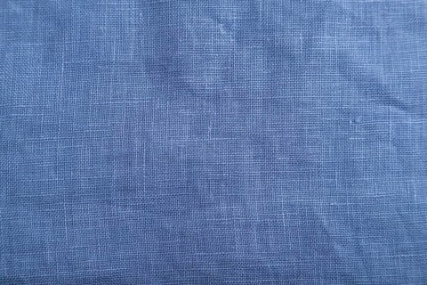 Fragment of smooth blue linen tissue. Top view, flat lay, natural textile background and texture