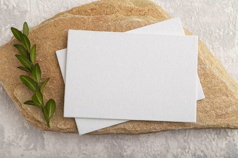 White paper business card, mockup with natural stone and boxwood branch on gray concrete background