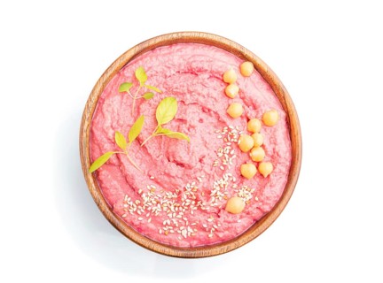 Hummus with beet in wooden bowl isolated on white background. Top view, flat lay, close up