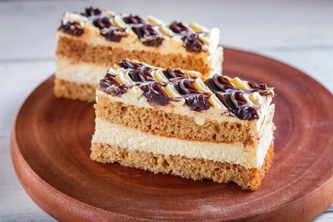 A piece of cake with milk and butter cream on a wooden kitchen board, close up, selective focus,