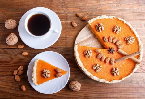 Traditional american sweet pumpkin pie decorated with nuts, on brown wooden background. cup of