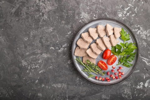 Boiled pork tongue with tomatoes and herbs on a black concrete background. Top view, copy space,