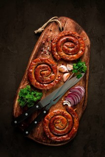 Fried spiral sausages, on a wooden board, top view, with spices, no people