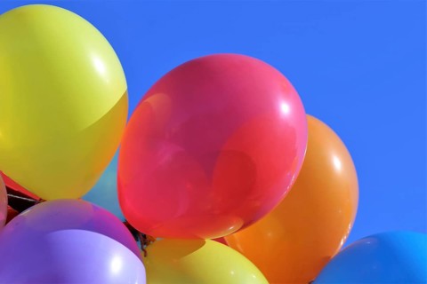 Close-up of colourful balloons against a blue sky