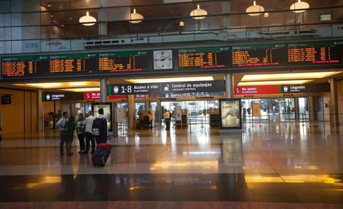Passengers looking at display board information inside, Maria Zambrano railway station, Malaga,