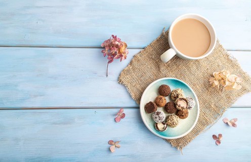 Chocolate truffle candies with cup of coffee on a blue wooden background and linen textile. top