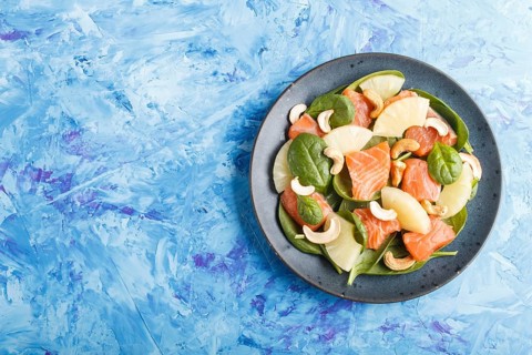 Fresh salmon with pineapple, spinach and cashew on a blue concrete background. Top view, copy