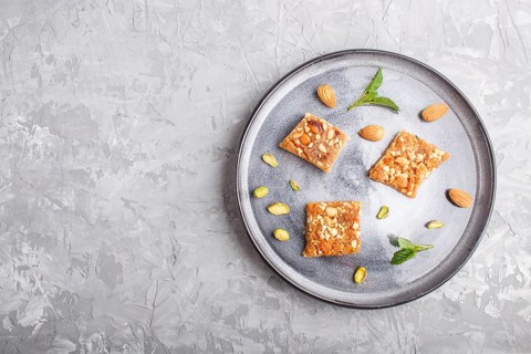 Traditional arabic sweets in gray ceramic plate on a gray concrete background. top view, copy space