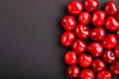 Cherries on black background, top view, flat lay, copy space