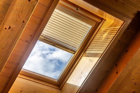 Interior view of a skylight with electronic blinds on a ceiling with wooden panelling