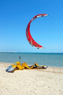 Red sail of kitesurfer kite surfer kite surfer standing close to viewer in the air above beach