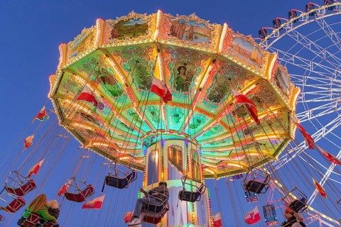 Illuminated carousel and Ferris wheel at night in a lively amusement park, funfair, wave flight,