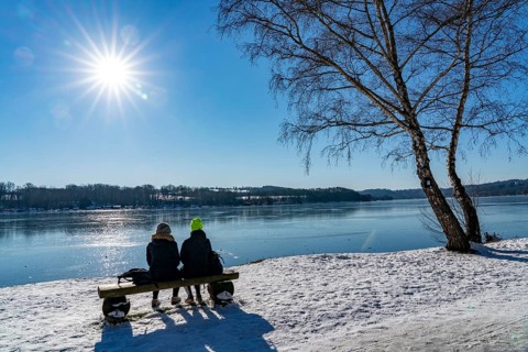 Winter in the Ruhr area, Lake Baldeney, snow-covered, partly frozen lake, walkers on the lakeside
