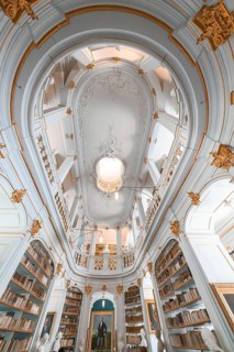 Old library with high ceilings, golden decorations and white walls that creates a calm atmosphere,