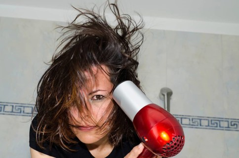 Portrait of a Beautiful Woman Drying Her Hair with a Hair Dryer in Bathroom in Switzerland