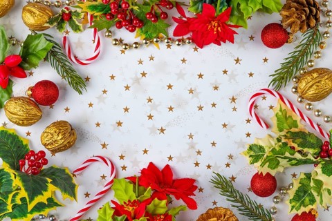 Frame made of Christmas decorations, such as fir branches, baubles, nuts, candy canes on a white