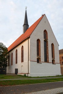 Gothic church with red tiled roof and high tower under a cloudy sky, St Augustin's Monastery