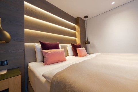 Modern bedroom with large bed, backlit wall and cosy atmosphere, Mayrhofen, Zillertal, Austria,