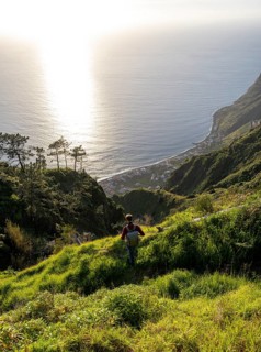 Young man looking out to sea on cliff, evening mood, green coastal landscape on cliff, sea and