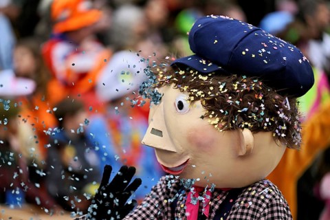 Person masked as a little boy with confetti in his hair at the carnival parade of the Wey guild on