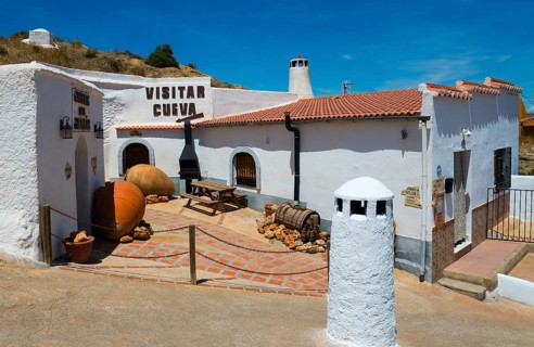 A traditional Spanish village with white buildings and clay jars under bright sunshine, Cueva del