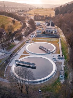 Aerial view of a sewage treatment plant focussing on the round clarifiers next to a forest, Nagold,