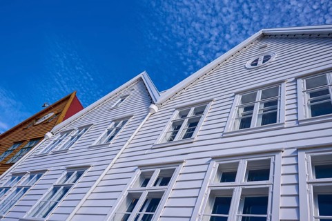 Traditional wooden houses under a blue sky with pitched roofs and multiple windows in a sunny old