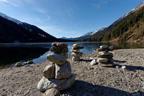 Cairns in winter on the icy lake, Lake Antholz in the Antholz Valley, Val Pusteria, South Tyrol,