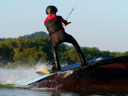 Young man with wakeboard on obstacle, water sports, water skiing in wakepark