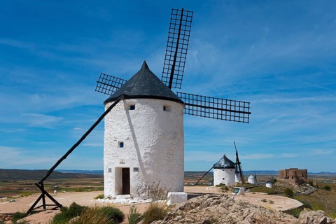 Several white windmills under a clear sky in a wide, sunny landscape, Consuegra, Toledo,