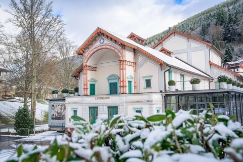 Historic theatre in a snow-covered winter landscape with wooded mountains in the background, Royal